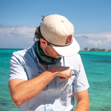 man reaching into pocket of blue short sleeve shirt