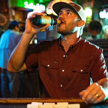 man drinking beer in short sleeve maroon shirt