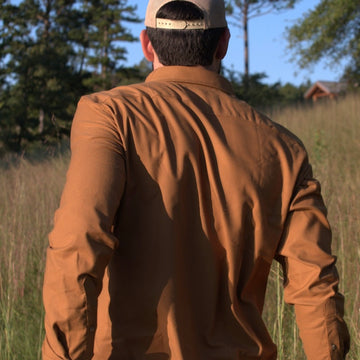 man walking through field in tan shirt