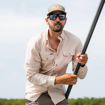 man wearing peach plaid shirt gripping pole