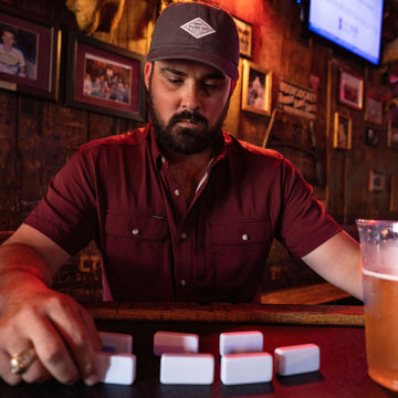 man playing dominos in maroon short sleeve shirt