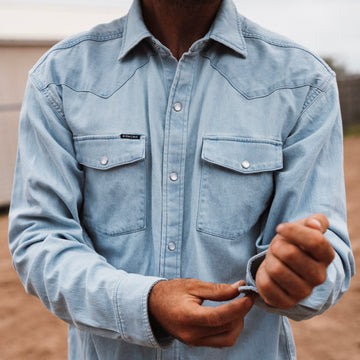 Man buttoning up denim shirt