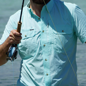 man with fishing rod wearing short sleeve green shirt