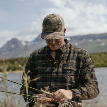 man holding fly rods wearing camo trucker hat
