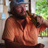 man drinking beer in orange short sleeve shirt