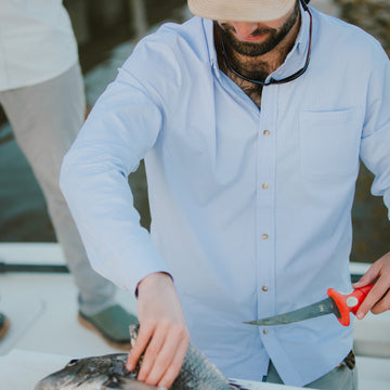 man cleaning fish in blue and plaid button up