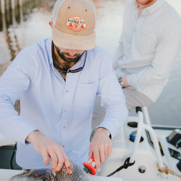 man cleaning fish in micro check blue fishing shirt