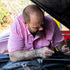 Man in The Foreman pink breathable outdoor shirt fixing a car engine