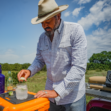 man fixing drink in blue plaid shirt