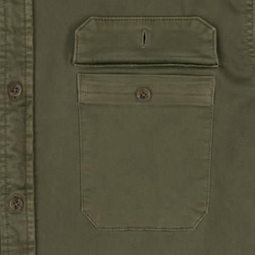 Close-up of an olive green shirt pocket with a flap and button detail from The Buck Snort collection.