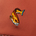 Embroidered orange and yellow fish with blue tail detail on reddish-brown fabric background.