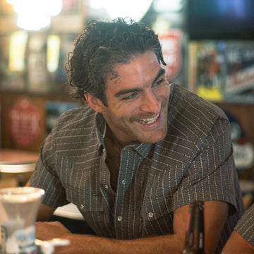 man smiling with grey and white short sleeve shirt