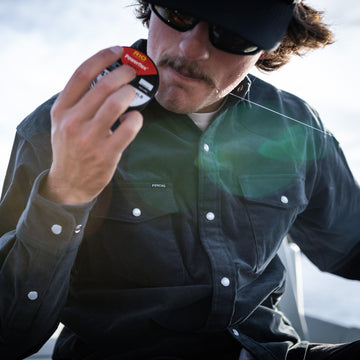 Man cutting fishing line with his mouth in a corduroy shirt