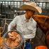 man putting a saddle on a horse wearing a long sleeve pearl snap shirt