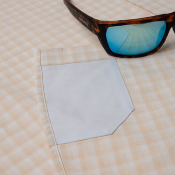 Close up of sunglass cleaner fabric on peach plaid fishing shirt