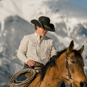 man riding horse with mountains in background