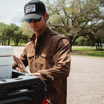 man closing truck tailgate in brown long sleeve shirt