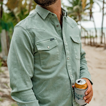 man holding beverage wearing green pearl snap  denim shirt