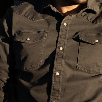 Detail shot of man wearing dark grey denim shirt at sunset