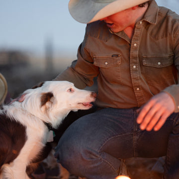 Man petting dog in brown denim shirt