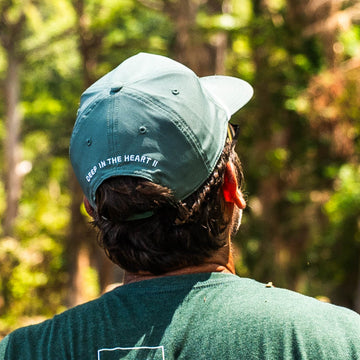 The Deep in the Heart Hat worn by a person exploring a sunlit forest