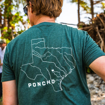 The Deep In The Heart T-Shirt featuring a white Texas outline graphic on a teal shirt worn outdoors