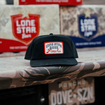 The Dive Hat black brimmed hat with a Lone Star Beer Poncho patch displayed on a counter