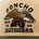 Close-up of a beige cap embroidered with a flying eagle holding a fish, featuring the text Poncho Outdoors Wild Free TX US.