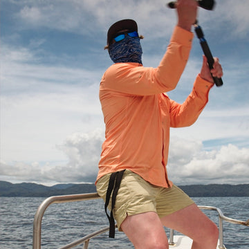 man casting fishing pole in orange shirt