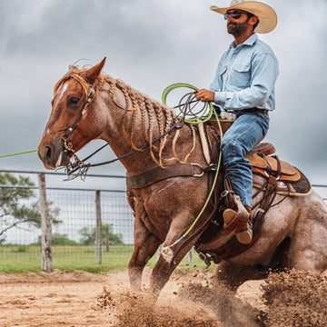 Cowboy riding horse in a denim shirt