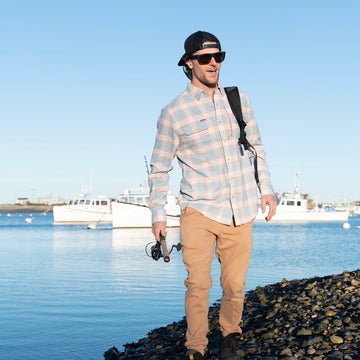 man carrying fishing pole on beach