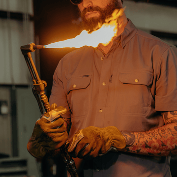Man working in grey button down work shirts with flame thrower