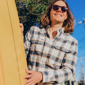 Man with surfboard and sunglasses wearing the half moon shirt