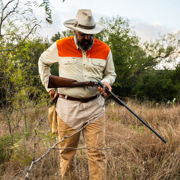man loading shotgun wearing long sleeve tan blaze patch shirt