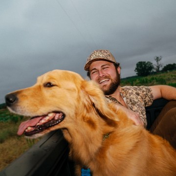 The Game Hat worn by a smiling man beside a happy golden retriever outdoors