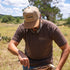 Man cutting meat wearing a poncho trucker hat