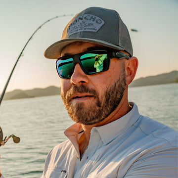 Man holding fishing rod with grey agave trucker hat