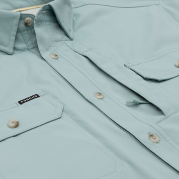 close up of pockets on light blue fishing shirt