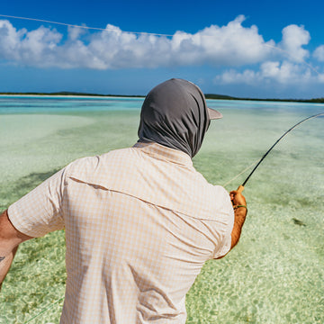 man casting fly rod with peach short sleeve shirt