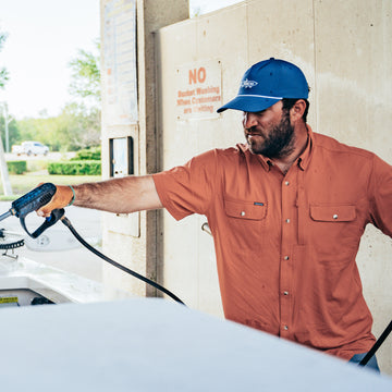 man filling up boat wearing clay color short sleeve shirt