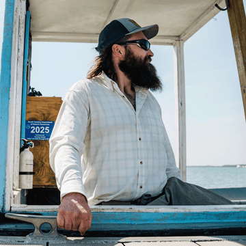 man sitting in boat wearing green plaid button down long sleeve shirt