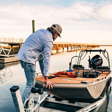 man launching boat in blue plaid long sleeve