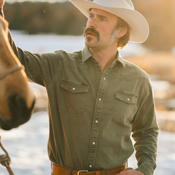 Man petting horse in green denim shirt