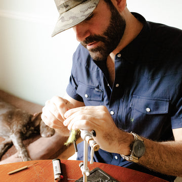 man wearing short sleeve navy shirt while tying flies