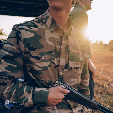man wearing camo long sleeve shirt holding shtgun