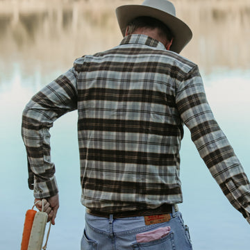 man throwing dog toy in blue and brown plaid flannel