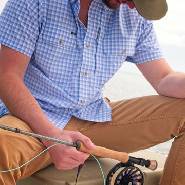 closeup of man holding rod wearing blue plaid short sleeve shirt