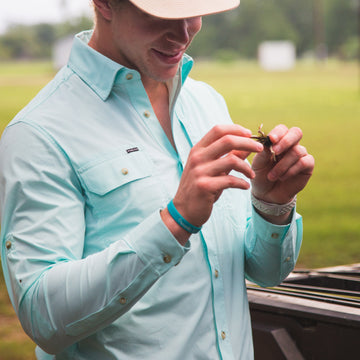 man holding fly wearing light green long sleeve shirt