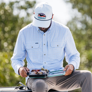 man looking at fly box wearing grey plaid long sleeve shirt