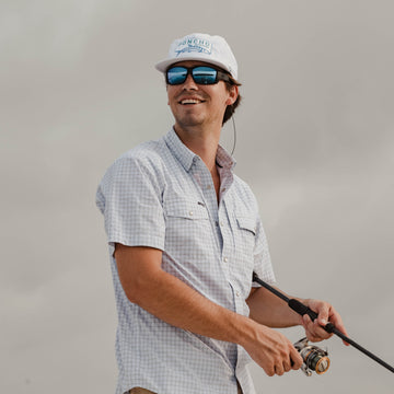 man smiling holding fishing rod wearing plaid short sleeve western